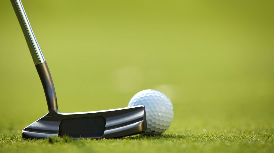 Close up of golf ball and putter on grass