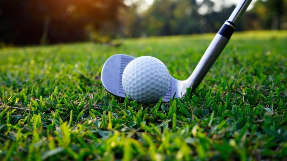 Close up of golf ball and club on wet grass