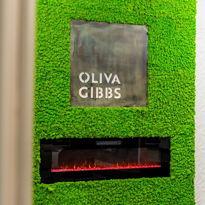 Wall plaque with Oliva Gibbs logo above fireplace
