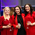 Three women wearing red pose for a photo at NAPE Charities Concert