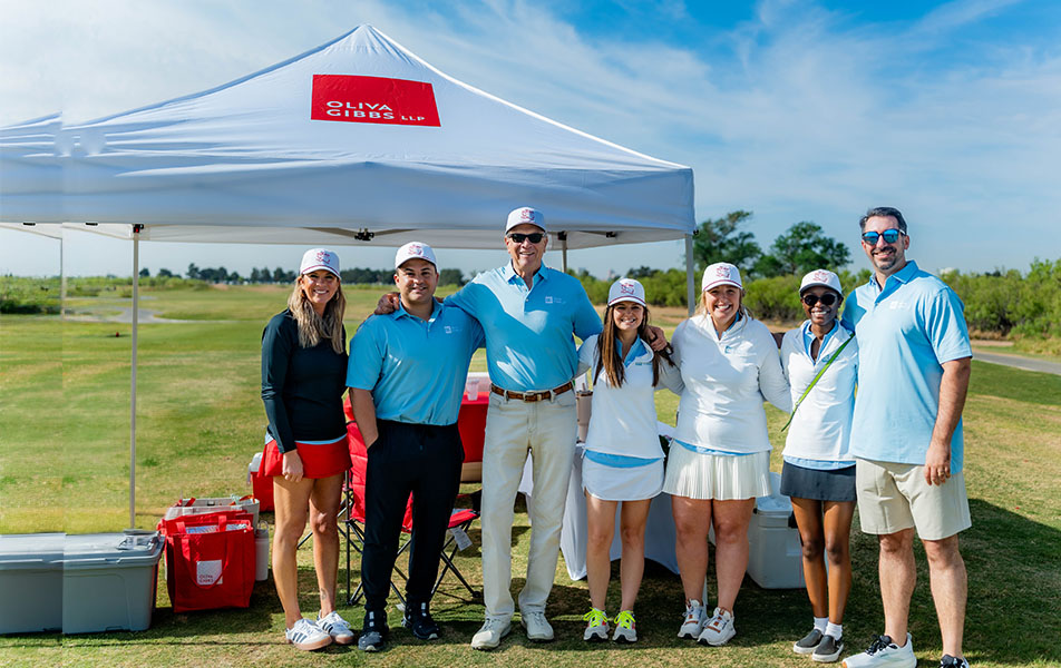 Oliva Gibbs team photo in front of branded tent on a golf course