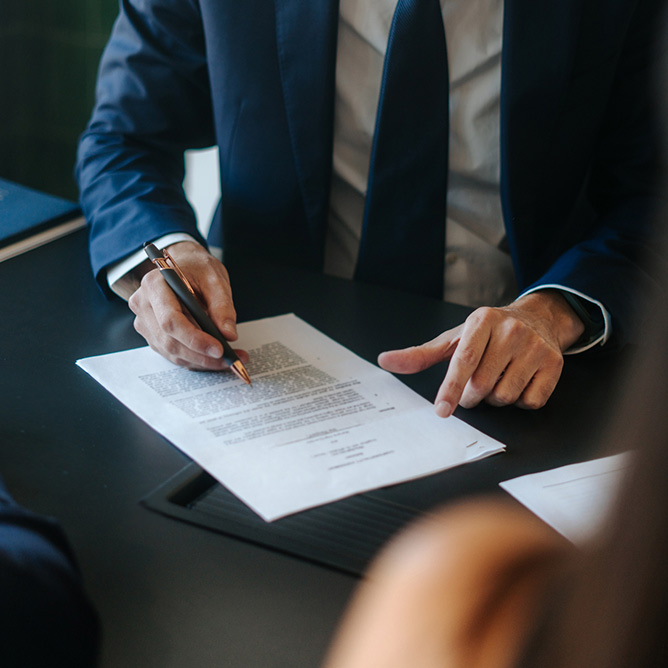 Man in a suit sitting at a table signing an agreement