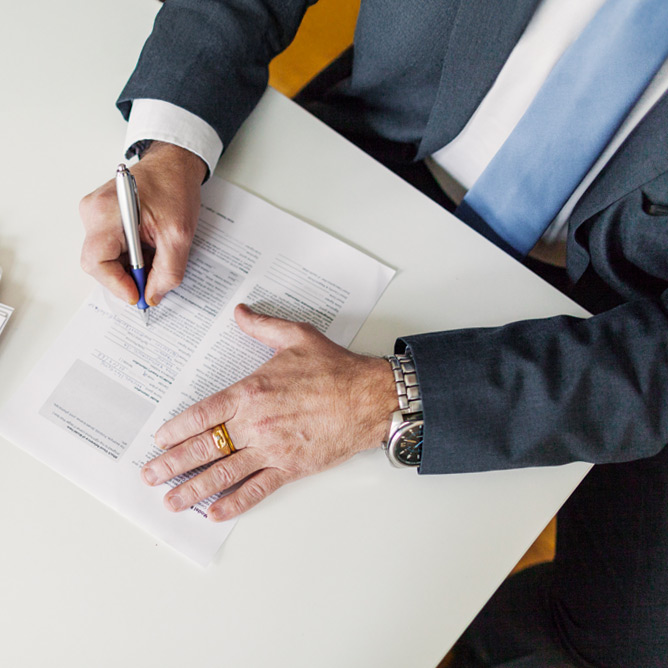 High angle view of businessman signing document at desk in office