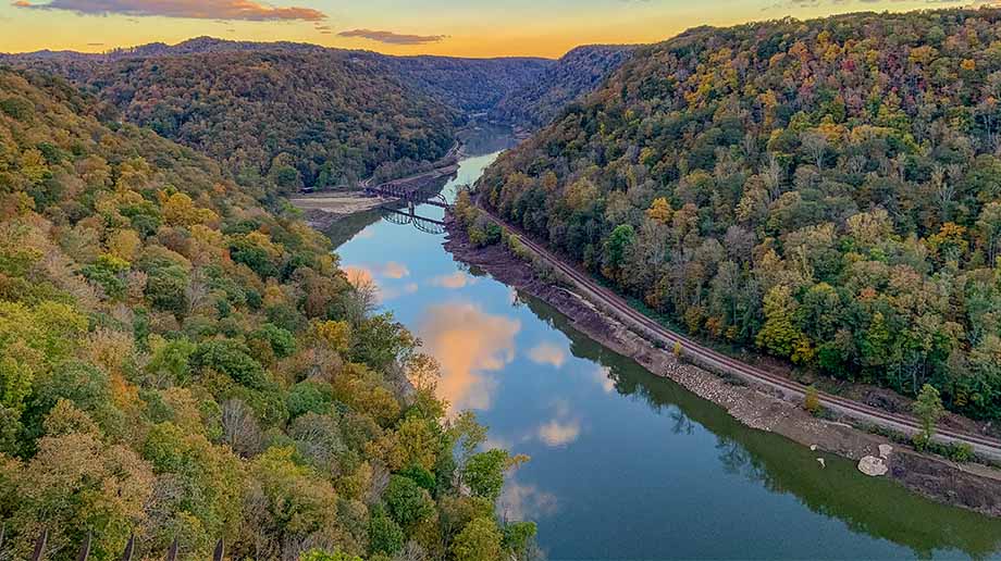 Aerial view of a river at sunset with forested hills on each side